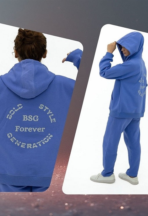 Person wearing a blue tracksuit with text on the back, standing against a white background.