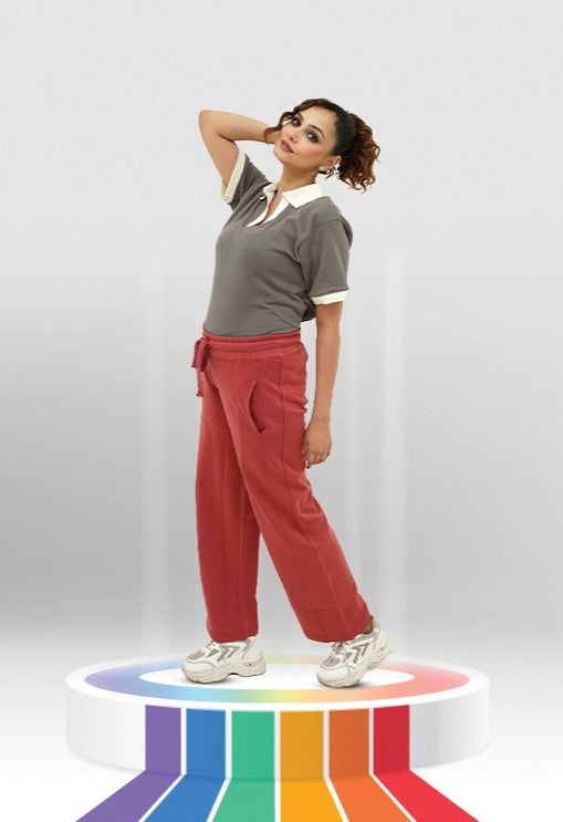 Woman in BSG brown shirt and red pants standing on a colorful platform with a white background
