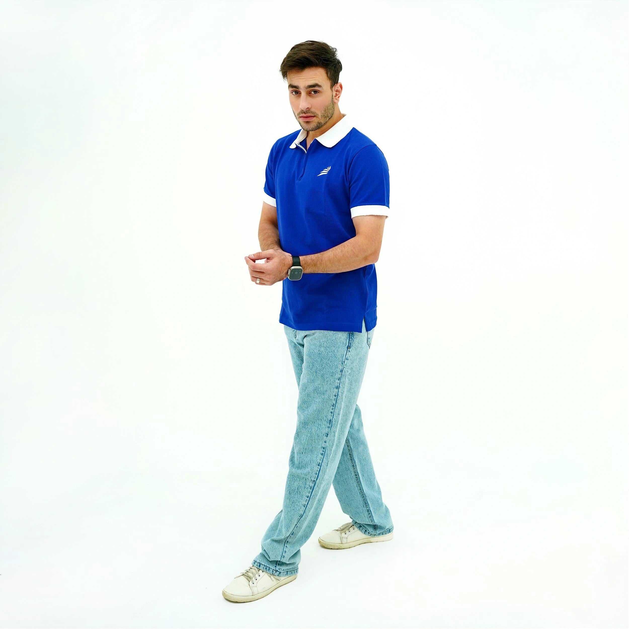 Man wearing a blue polo shirt with a white collar and light blue jeans on a white background