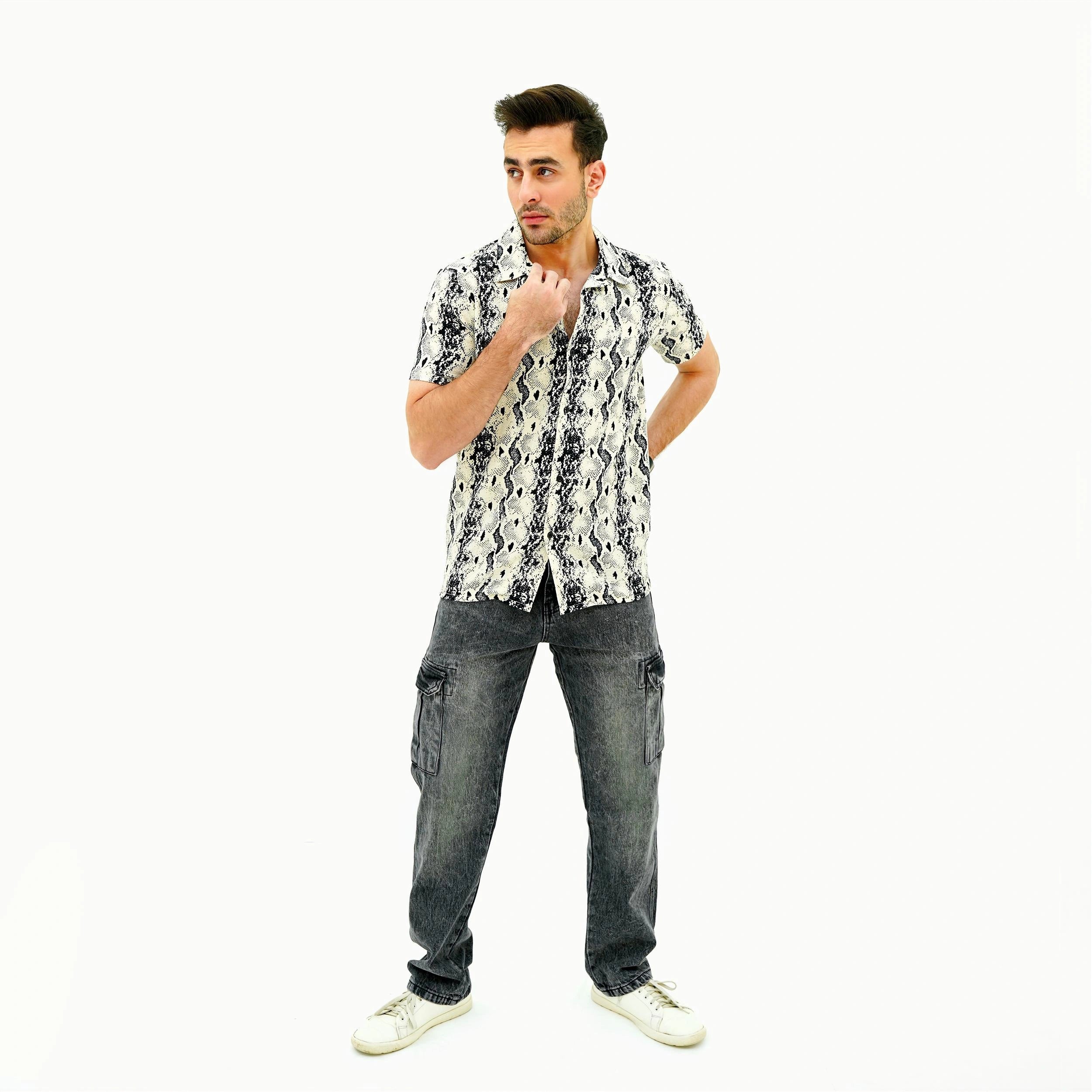 Man wearing a patterned shirt and jeans on a white background