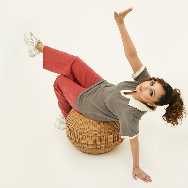 Person wearing BSG outfit and sitting on wooden chair on a white background