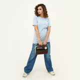 Woman wearing BSG Azure Noir Chic Contrast Tee Shirt in light blue with short sleeves holding a retro-style radio