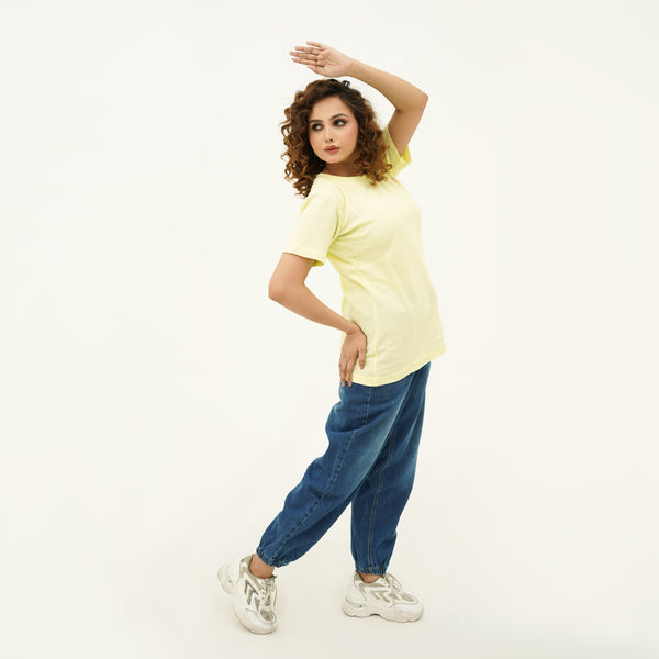 Woman wearing light yellow Citrus Weave Breeze Tee Shirt paired with blue jeans and white sneakers