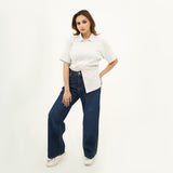 Woman wearing BSG Striped Cream Button Down Polo with short sleeves paired with dark blue wide-leg jeans