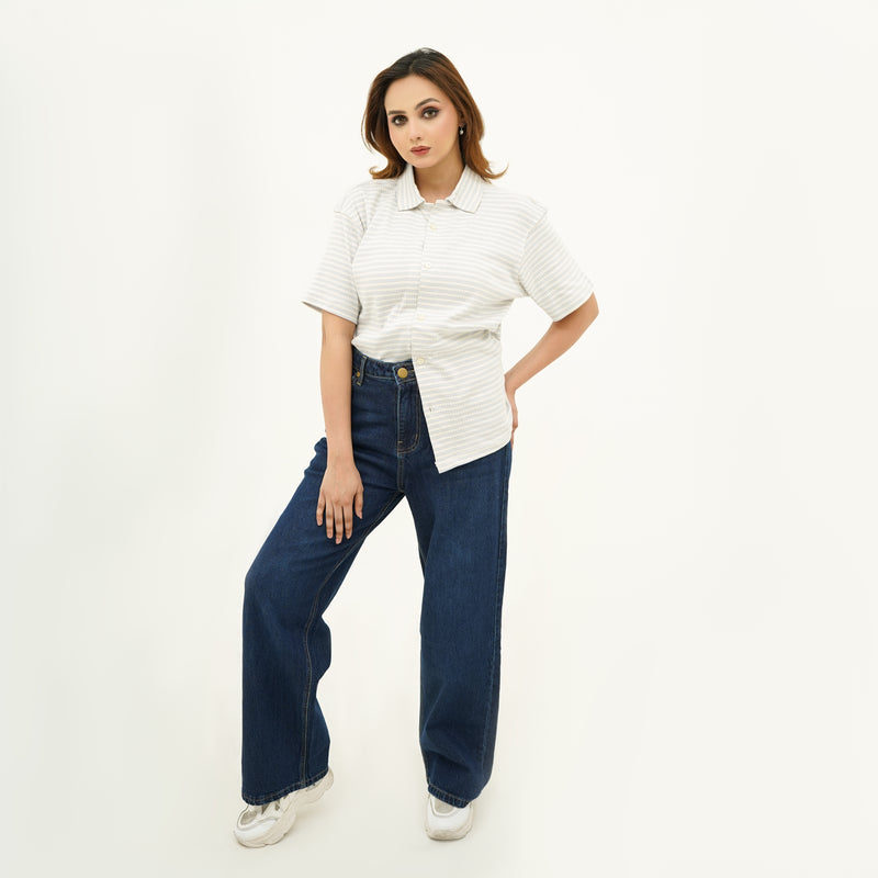 Woman wearing BSG Striped Cream Button Down Polo with short sleeves paired with dark blue wide-leg jeans